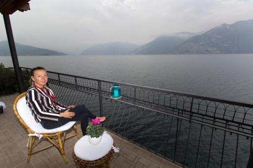a man sitting in a chair next to the water at FIDES ON THE LAKE in Marone