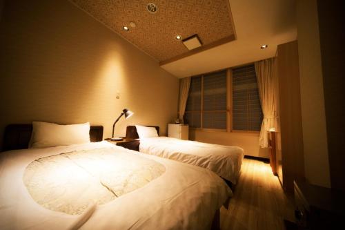 a bedroom with two beds and a window at Aizu Higashiyama Onsen Tsuki no Akari in Aizuwakamatsu
