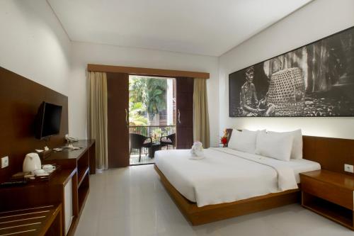 a bedroom with a large white bed and a television at New Garden View Resort in Legian