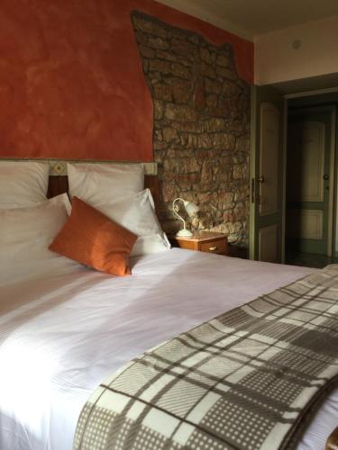 a bedroom with a large white bed with a stone wall at Albergo Ristorante Leso in Bosco Chiesanuova