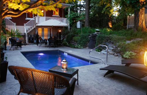 una piscina en un patio con sillas y mesa en Au Virage B&B en Magog-Orford