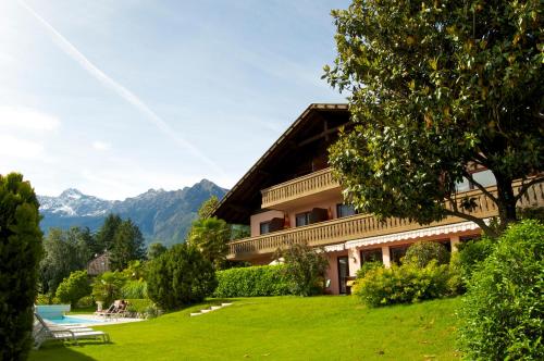 a house in the mountains with a green lawn at Hotel Schönbrunn in Merano