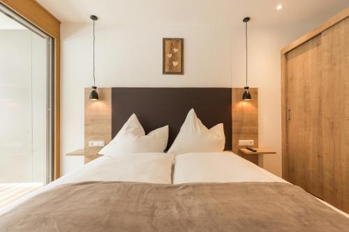 een slaapkamer met een groot bed met witte kussens bij Apartment Waldesruh in Oetz
