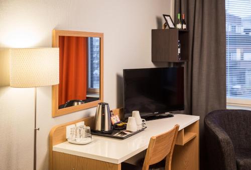 a hotel room with a desk with a television and a mirror at Park Hotel Tornio in Tornio