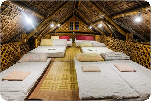 a room with four beds in a straw hut at Darpins Guesthouse in Dauin