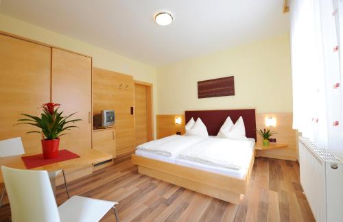 1 dormitorio con cama blanca, mesa y escritorio en Weingut & Gästezimmer Nekowitsch en Illmitz