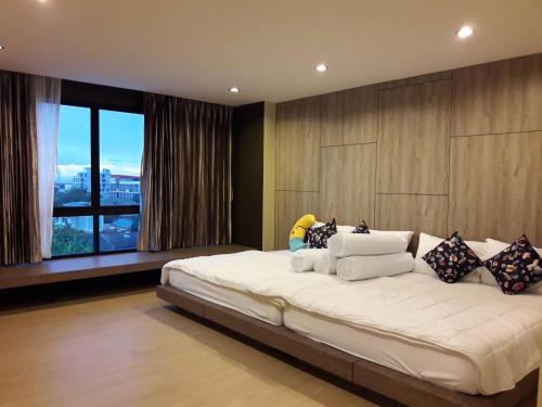 a bedroom with a large bed with a large window at The Residence Thepkanjana in Ban Khlong Krathum Baen