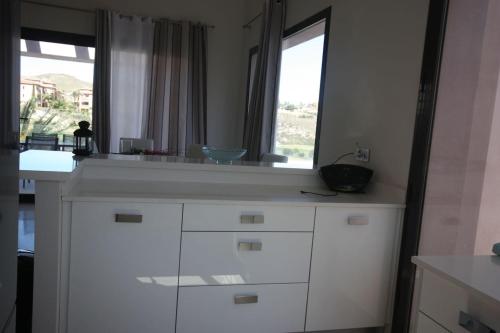 a kitchen with white cabinets and a large window at Casa Nimajas in Vera