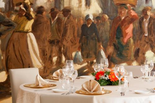 a table with white plates and glasses and a painting at Hotel Tropis in Tropea