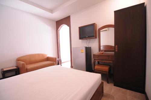 um quarto com uma cama, uma secretária e uma televisão em Paradise Inn and Dining em Saraburi