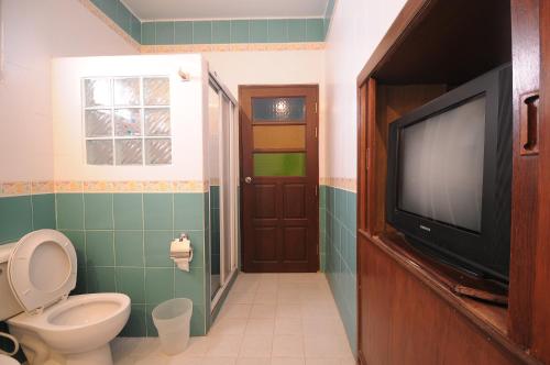 a bathroom with a toilet and a flat screen tv at Paradise Inn and Dining in Sara Buri