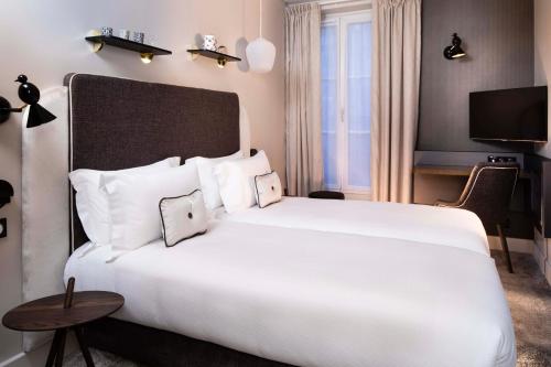 a bedroom with a large white bed and a tv at Hôtel Eiffel Saint Charles in Paris
