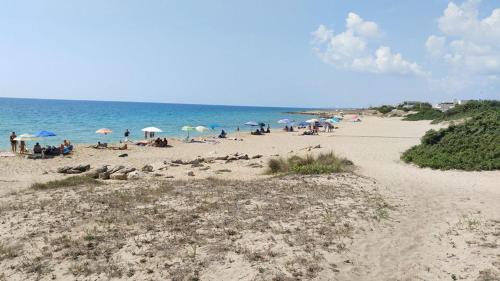 um grupo de pessoas sentadas numa praia com guarda-sóis em Forte apartments "Enjoy Salento" em Avetrana