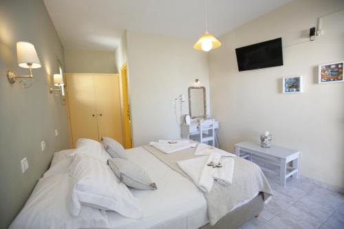 a bedroom with a bed with white sheets and a mirror at Alexandra's Rooms in Parikia