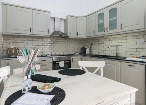 a kitchen with white cabinets and a white table and chairs at Uncle's House luxury Suites in Adamas