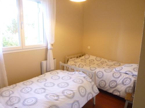 zwei Einzelbetten in einem Zimmer mit Fenster in der Unterkunft 18 Résidence Parc de la Dune in Lacanau