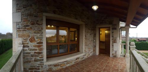 a stone house with a porch with a window at Casa Loisiana in O Pino 