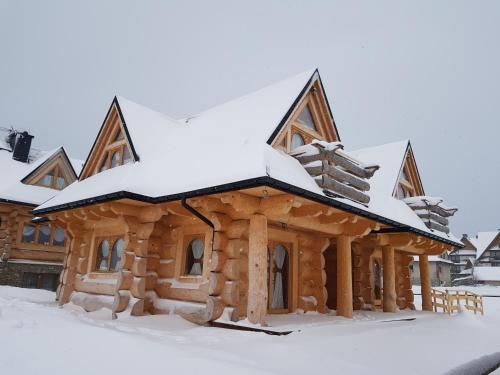 una cabaña de madera cubierta de nieve en Domek w Białce en Białka Tatrzanska