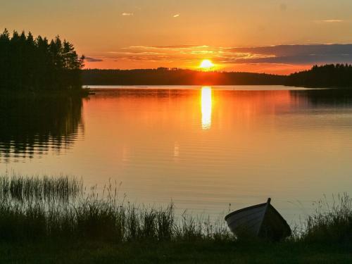 a boat sitting on the shore of a lake at sunset at Holiday Home Viehko by Interhome in Lipinlahti