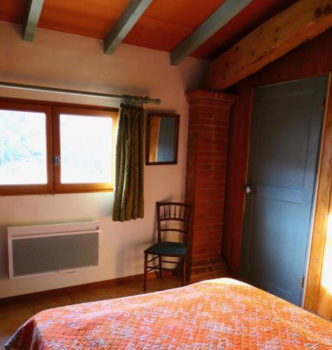 une chambre avec un lit, une chaise et une fenêtre dans l'établissement Coutelon, havre de paix en pleine nature, à Saint-Jurs