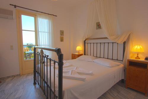 Schlafzimmer mit einem Bett mit weißer Bettwäsche und einem Fenster in der Unterkunft Swiss Home Hotel in Naoussa