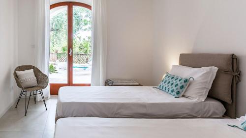a bedroom with two beds and a chair and a window at La Matrangela Charme Apartments in Taormina
