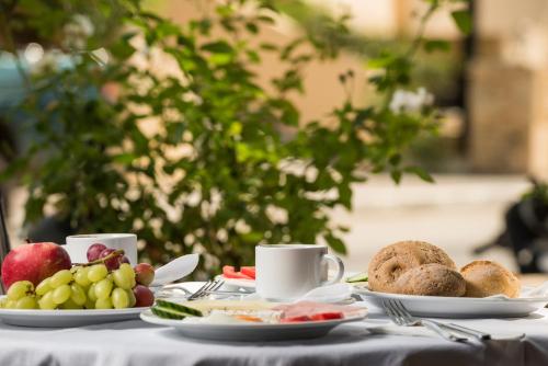 a table topped with plates of fruit and coffee cups at Elotis Suites in Agia Marina Nea Kydonias