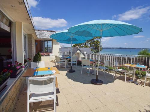 een patio met tafels, stoelen en parasols bij Logis Hotel Belle-Vue in Fouesnant