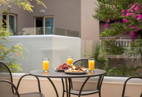 a table with a plate of food and two glasses of orange juice at Elotis Suites in Agia Marina Nea Kydonias