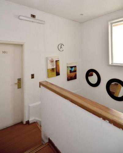 a hallway with white walls and a staircase with art on the wall at Hotel Boutique Trinidad in Viña del Mar