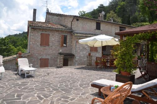 a patio with chairs and an umbrella in front of a house at B&B La Terrazza Del Subasio in Assisi