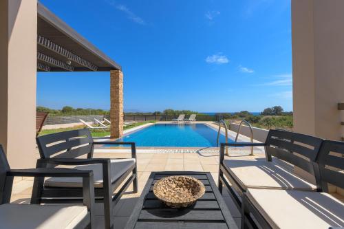 eine Terrasse mit 2 Stühlen und einem Pool in der Unterkunft Blue Wave Villa in Gennadi