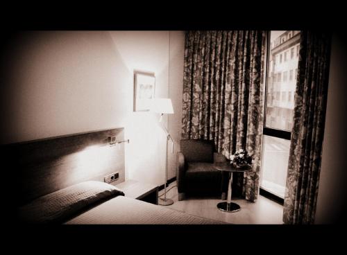 a hotel room with a bed and a chair and a window at Hotel Mieres del Camino in Mieres