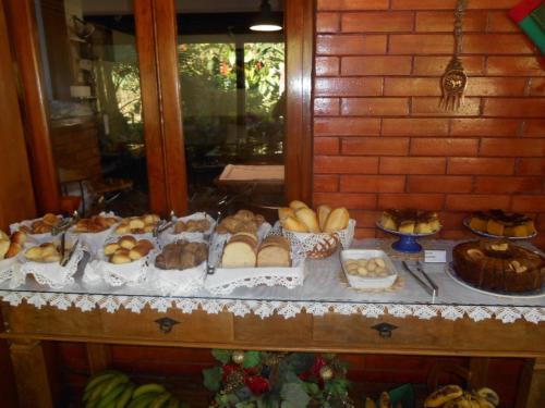 a table filled with different types of bread and pastries at Pousada Penedo in Penedo