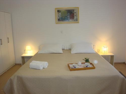 a bed with two towels and a tray with two dolls at Apartments Olea in Pinezici