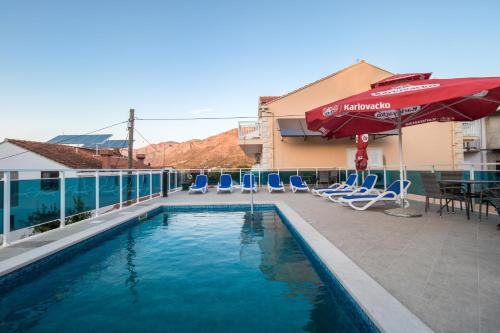 a pool on the roof of a hotel with chairs and an umbrella at Villa Voinic 2 in Cavtat