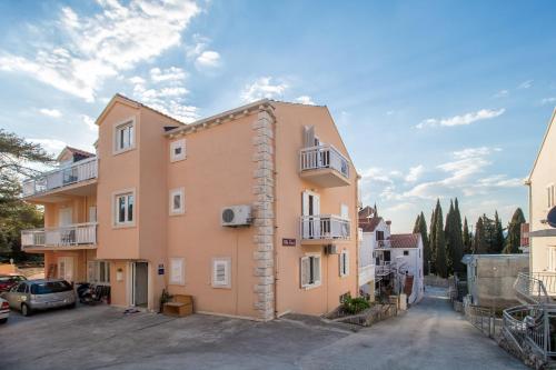 a pink building with a parking lot in front of it at Villa Voinic 2 in Cavtat
