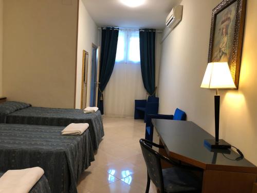 a hotel room with a desk and a bed and a table at Hotel Chopin in Fiumicino