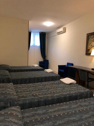 a hotel room with three beds and a desk at Hotel Chopin in Fiumicino