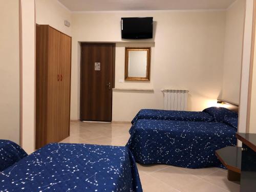 a bedroom with two beds and a television on the wall at Hotel Chopin in Fiumicino