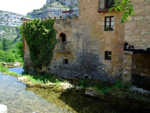 an old stone building next to a river at Hotel Rural La Puebla in Orbaneja del Castillo