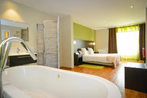 a bathroom with a tub and a bedroom with a bed at Logis Hôtel Restaurant l'Auberge Normande in Carentan