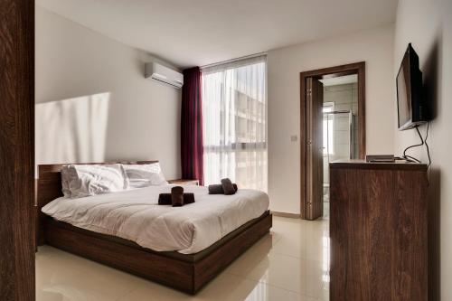 a bedroom with a bed and a television in it at The Village Apartments in St Paul's Bay