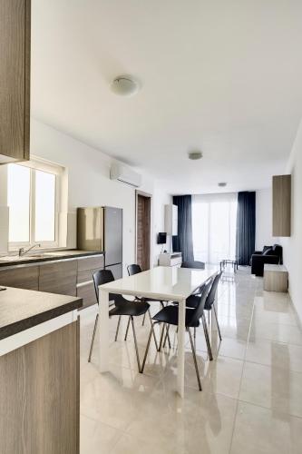 a kitchen and dining room with a table and chairs at The Village Apartments in St. Paul's Bay