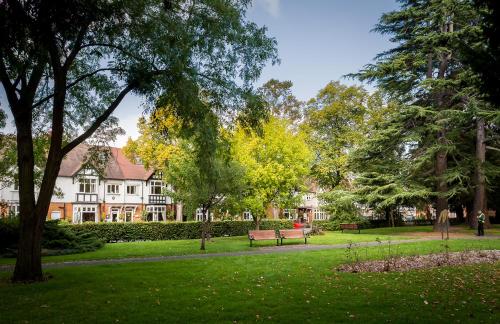 a park with a bench and trees and buildings at Ashgrove House in Stratford-upon-Avon