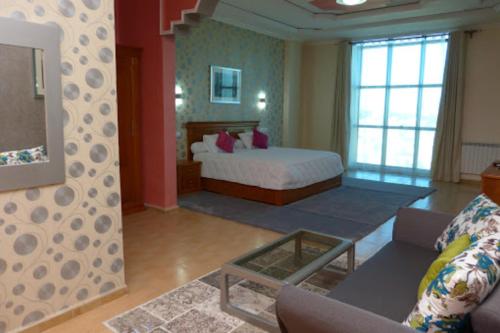 ein Schlafzimmer mit einem Bett und ein Wohnzimmer mit einer Couch in der Unterkunft MARAVAL in Oran