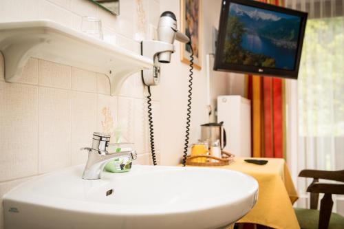 a bathroom with a white sink and a tv at Gästehaus Haffner in Zell am See