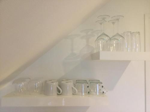a shelf with glass mugs and vases on it at De Fugelsang in Jonkersland