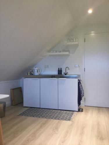 a kitchen with white cabinets and a sink at De Fugelsang in Jonkersland