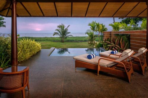 a patio with a table and chairs and a pool at Niraamaya Wellness Retreats Backwaters And Beyond Kumarakom in Kumarakom